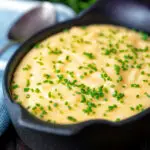 Close up creamy cheesy polenta garnished with snipped chives.