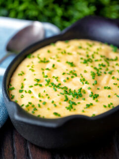 Close up creamy cheesy polenta garnished with snipped chives.
