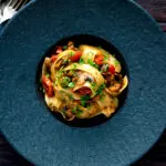 Overhead chorizo pasta with pappardelle, tomatoes and mushrooms.