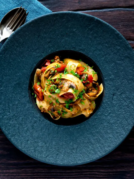 Overhead chorizo pasta with pappardelle, tomatoes and mushrooms.