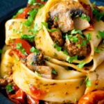 Close up chorizo pasta with pappardelle, tomatoes and mushrooms.