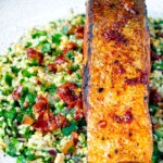 Close up pan fried harissa salmon fillet served with tabbouleh salad.