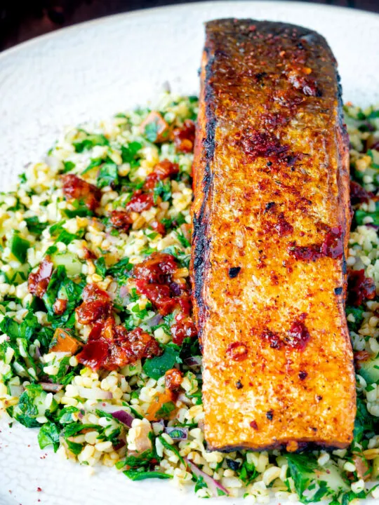 Close up pan fried harissa salmon fillet served with tabbouleh salad.