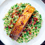 Overhead pan fried harissa salmon fillet served with tabbouleh salad.