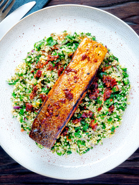 Overhead pan fried harissa salmon fillet served with tabbouleh salad.