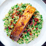 Overhead pan fried harissa salmon fillet served with tabbouleh salad featuring a title overlay.