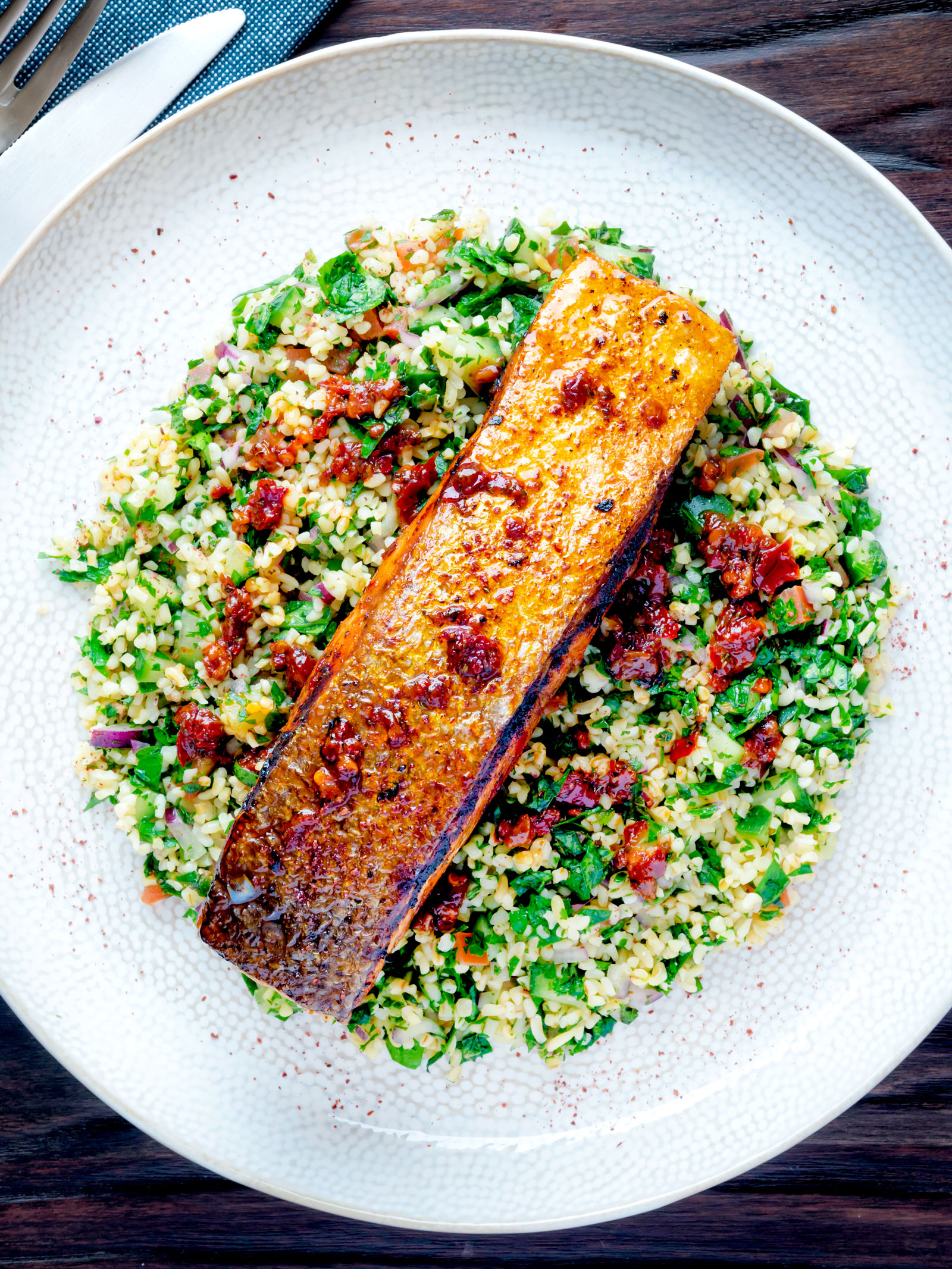 Overhead pan fried harissa salmon fillet served with tabbouleh salad.
