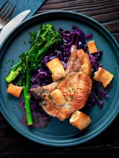 Overhead Instant Pot pork chops with red cabbage served with crispy crackling and broccoli.