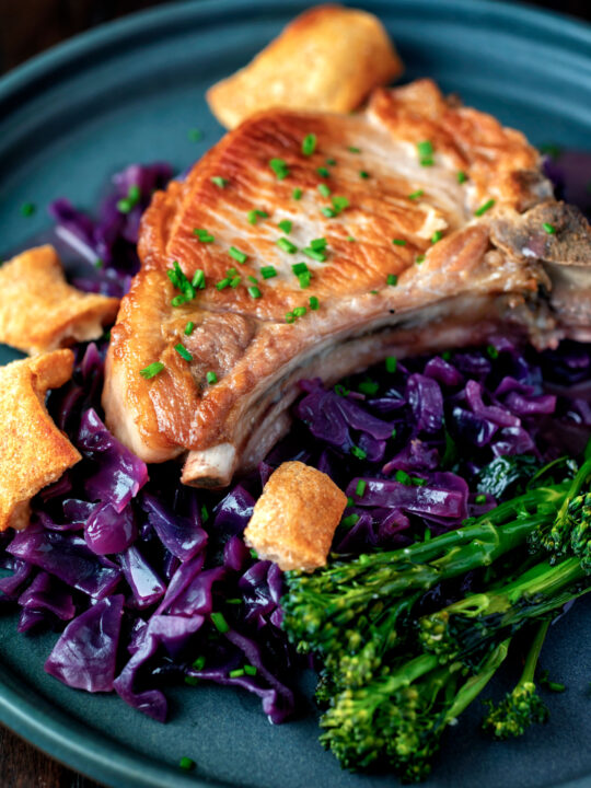 Close up Instant Pot pork chops with red cabbage, crispy crackling and broccoli.