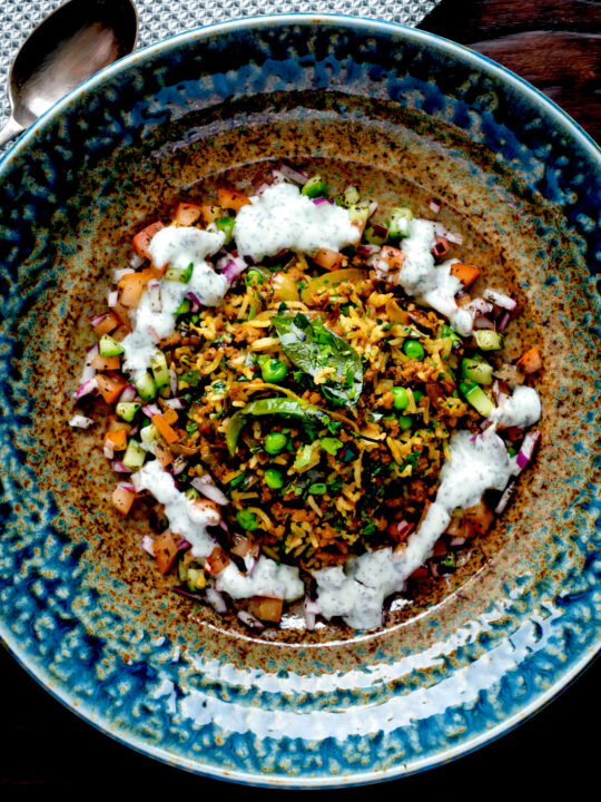 Overhead keema rice served with kachumber salad and mint raita.