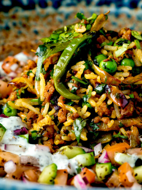 Close up keema rice served with kachumber salad and mint raita.