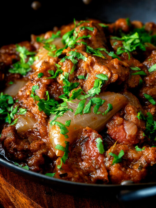 Close up lamb bhuna curry served in an iron karahi.