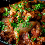 Close up lamb bhuna curry served in an iron karahi with naan bread featuring a title overlay.