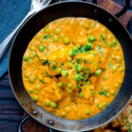 Overhead matar paneer curry served in an iron kadai with fresh coriander.