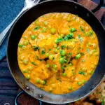 Overhead matar paneer curry served in an iron kadai with fresh coriander featuring a title overlay.