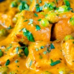 Close up matar paneer curry served in an iron kadai with fresh coriander.