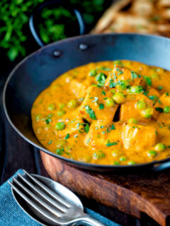 Matar paneer curry served in an iron kadai with fresh coriander.