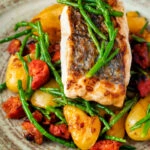 Close up pan fried hake with chorizo, new potatoes and samphire.