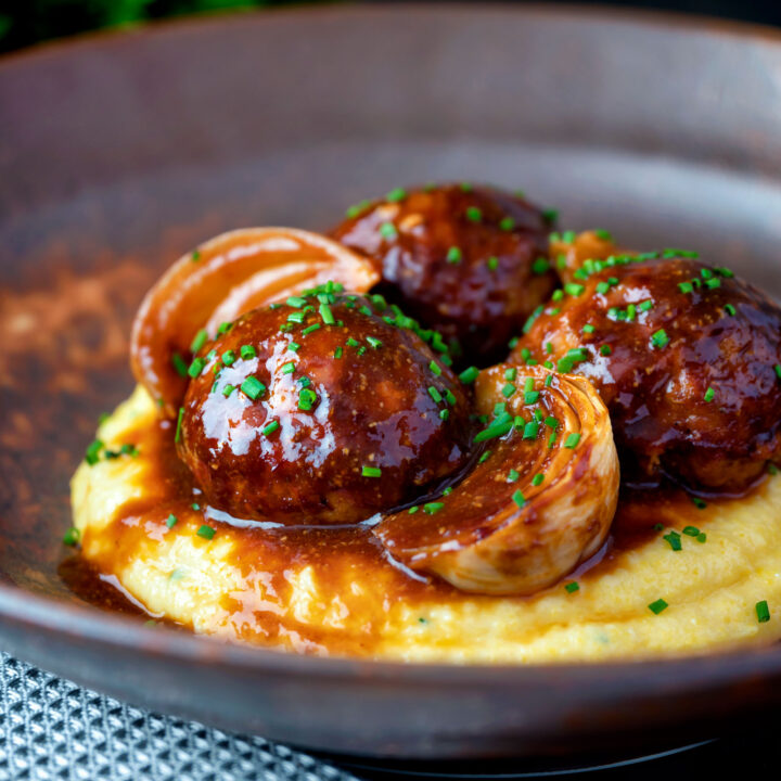 Pork meatballs with onion wedges in a beer BBQ sauce served on cheesy polenta.