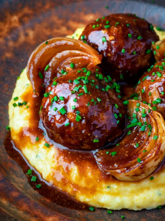 Close up pork meatballs in a beer BBQ sauce served on cheesy polenta.