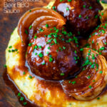 Close up pork meatballs in a beer BBQ sauce served on cheesy polenta featuring a title overlay.