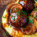 Close up pork meatballs in a beer BBQ sauce served on cheesy polenta featuring a title overlay.