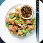Overhead salt and pepper tofu with a chilli soy dipping sauce and pickled cucumber.