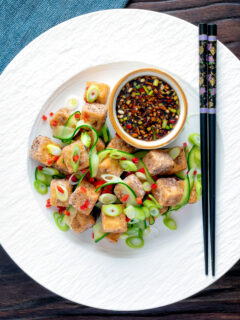 Overhead salt and pepper tofu with a chilli soy dipping sauce and pickled cucumber.