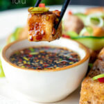 Salt and pepper tofu dipped into a soy and chilli dipping sauce featuring a title overlay.