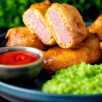 Cut open spam fritters served with mushy peas and ketchup.