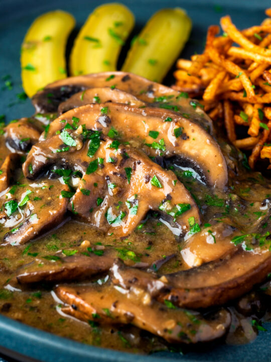 Close up vegan mushroom stroganoff served with pickles.