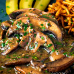 Close up vegan mushroom stroganoff served with pickles featuring a title overlay.