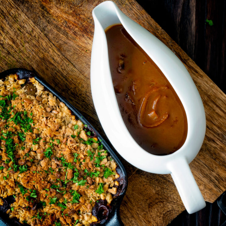 Vegan onion gravy served in a gravy boat with vegetable crumble.