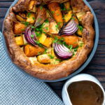 Overhead vegan onion gravy served with a vegetable toad in the hole featuring a title overlay.