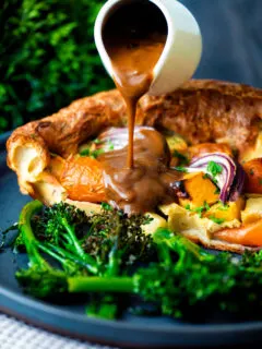 Vegan onion gravy being poured over a vegetable toad in the hole.