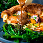 Vegan onion gravy being poured over a vegetable toad in the hole featuring a title overlay.