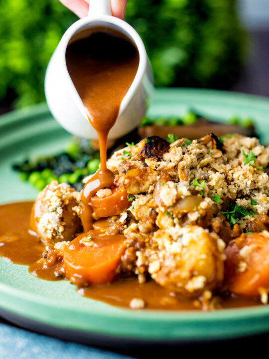 Vegan onion gravy poured over a root vegetable crumble featuring a title overlay.
