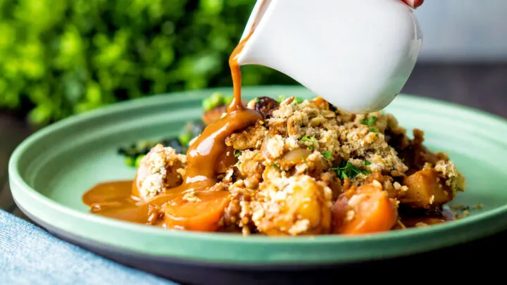 Vegan onion gravy poured over a root vegetable crumble.