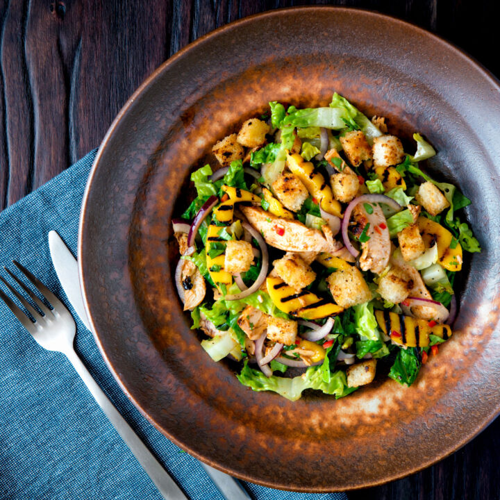 Spicy chicken and mango salad with croutons and red onion.