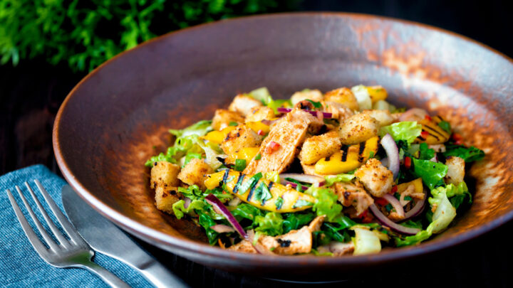 Spicy chicken and mango salad with croutons and red onion.