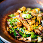 Warm chicken and mango salad with croutons and red onion.