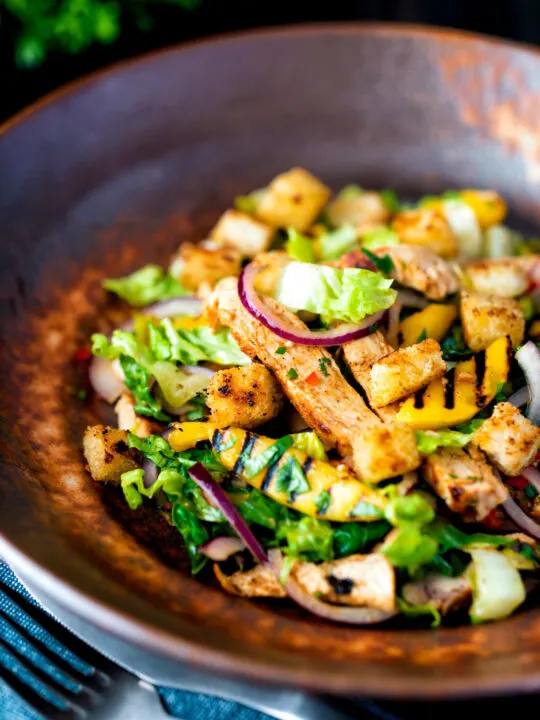 Warm chicken and mango salad with croutons and red onion.