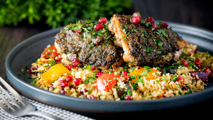 Baked chermoula chicken thighs served with roasted vegetable couscous and pomegranate.