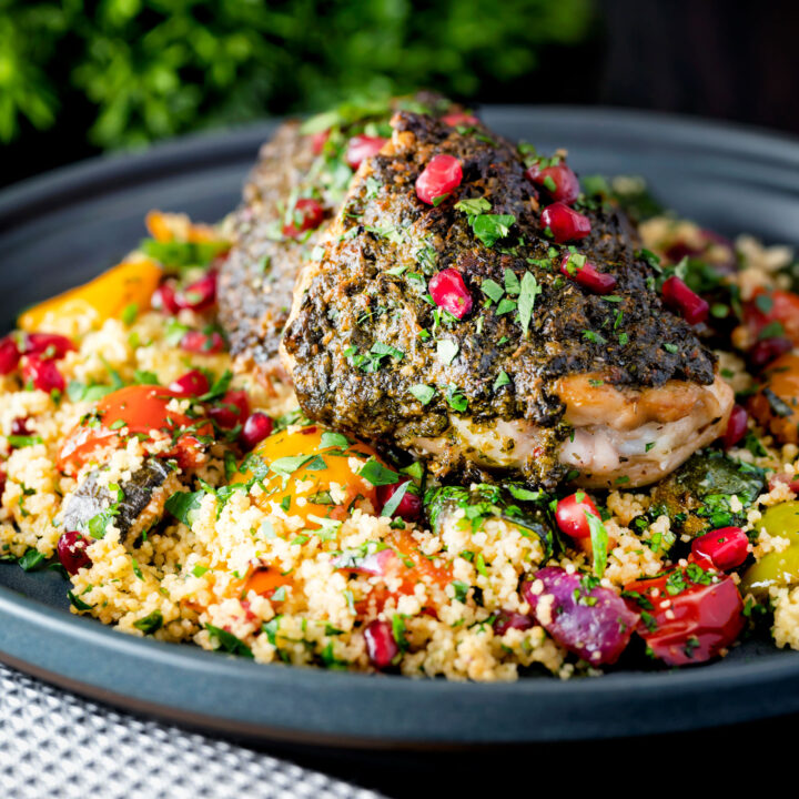 Baked chermoula chicken thighs served with roasted vegetable couscous and pomegranate.