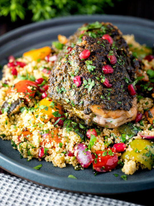 Baked chermoula chicken thighs served with roasted vegetable couscous and fresh herbs.