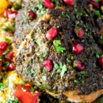 Close up chermoula chicken thighs served with roasted vegetable couscous and fresh herbs.