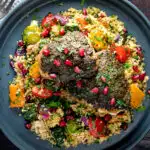 Overhead chermoula chicken thighs served with roasted vegetable couscous and fresh herbs featuring a title overlay.