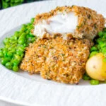 Baked cod loin in crispy panko breadcrumbs cut open to show flaky white fish.