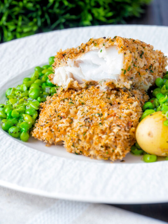 Baked cod loin in crispy panko breadcrumbs cut open to show flaky white fish.