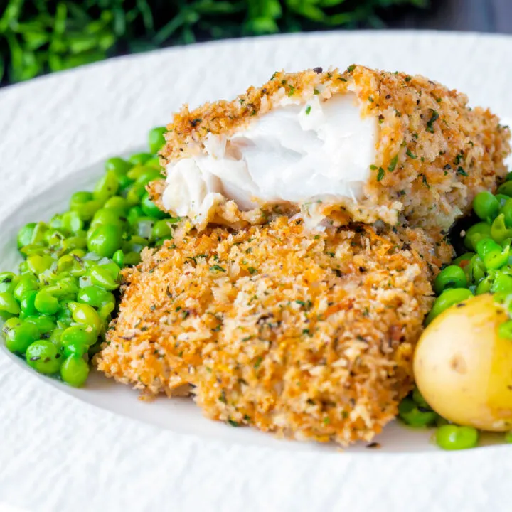 Baked cod loin in herbed panko breadcrumbs cut open to show flaky white fish.